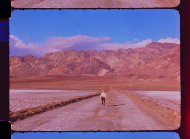 A woman walks down a road in a desert