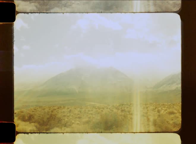 Landscape of desert vegetation with mountain ranges around and a strong solar reflection on a cloudy day