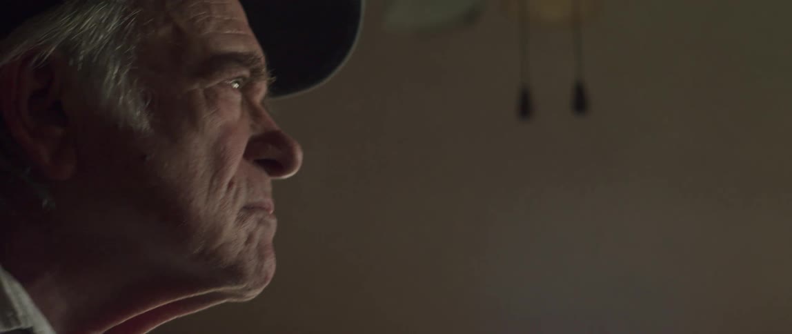 An older man stands in a room and walks toward the window