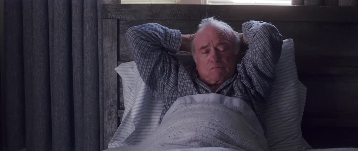A man lies in a bed while talking outloud