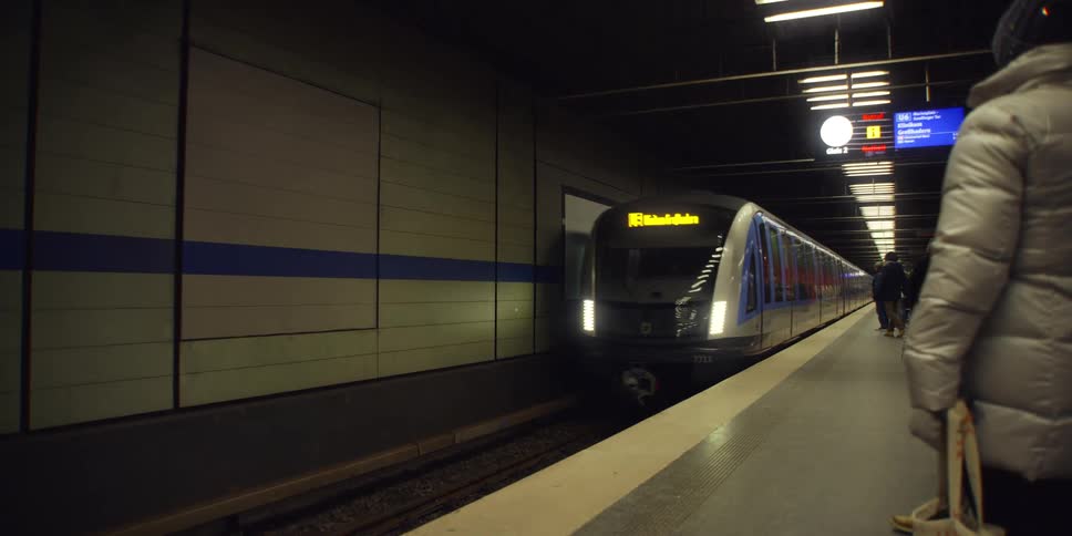 Train stopping at an indoor station with a crowd of passengers