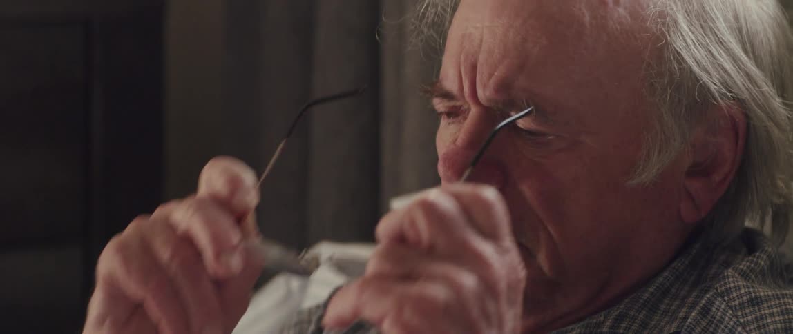 Side portrait of an elderly man with a surprised facial expression putting on his glasses and taking them off while talking