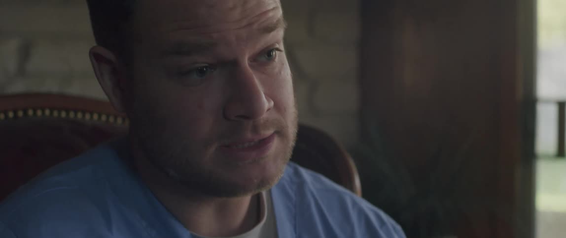 A man talks while sitting in a chair in a room