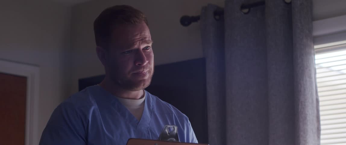 Male nurse holding a clipboard talking in a room