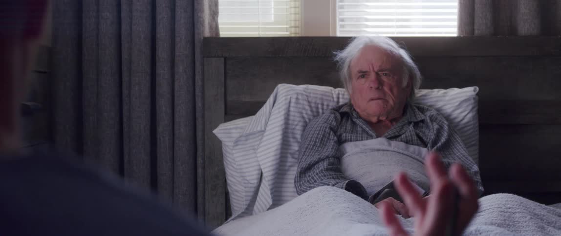Doctor talking to an elderly patient who is sitting on a bed