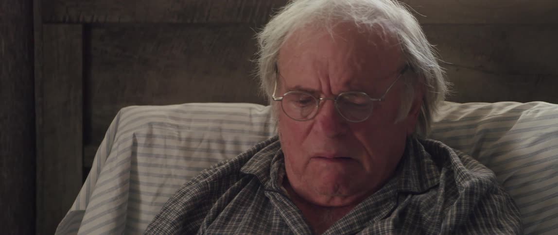 Elderly man resting in bed reads a document in disbelief
