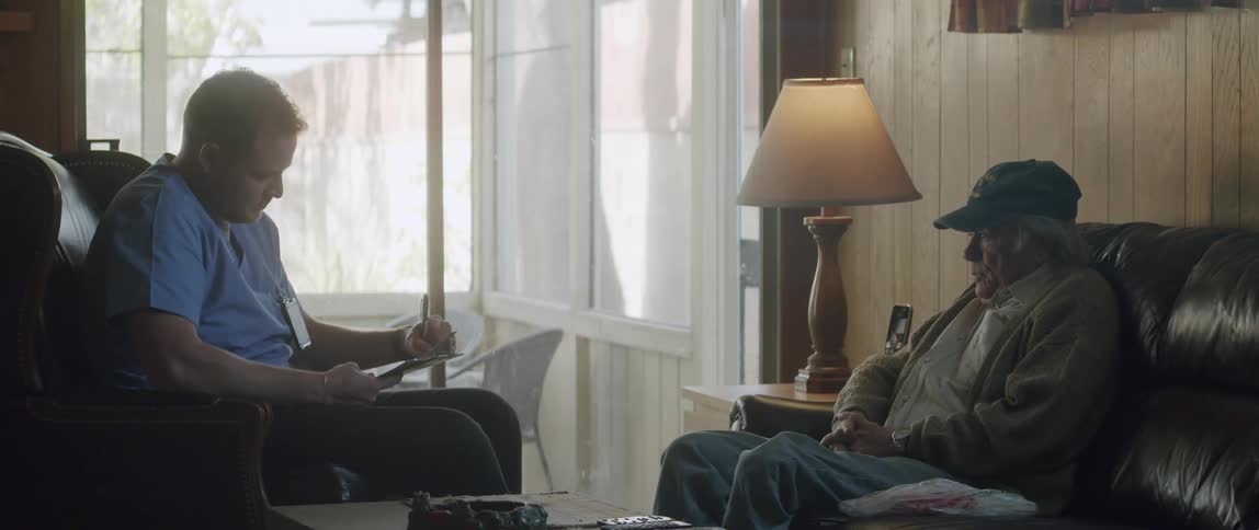 Doctor sitting in an armchair talking to his elderly patient