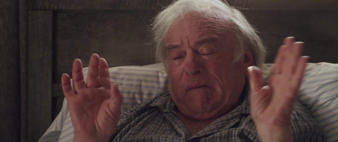 Portrait of an elderly man crying emotionally while sitting on the bed and talking