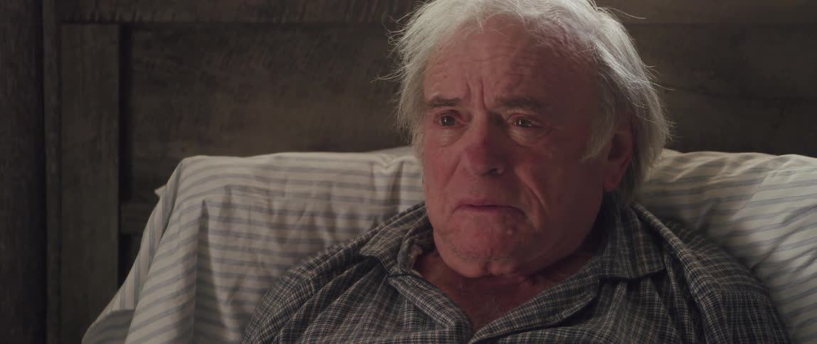 Portrait of an elderly man lying down with watery eyes talking with a mix of anger revolt and sadness