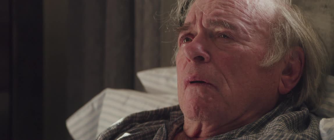 Sad elderly man holds tears while resting at bed