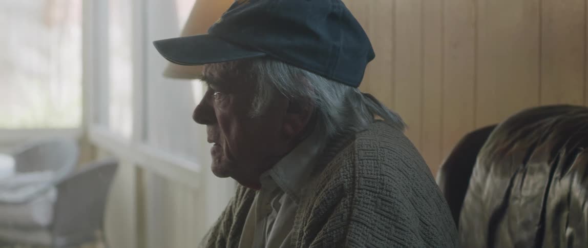 An old man becomes sad and adjusts himself in his seat