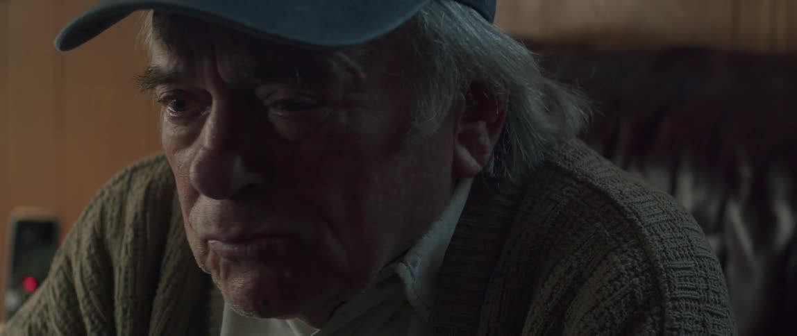 Elderly sitting man frowns while he talks