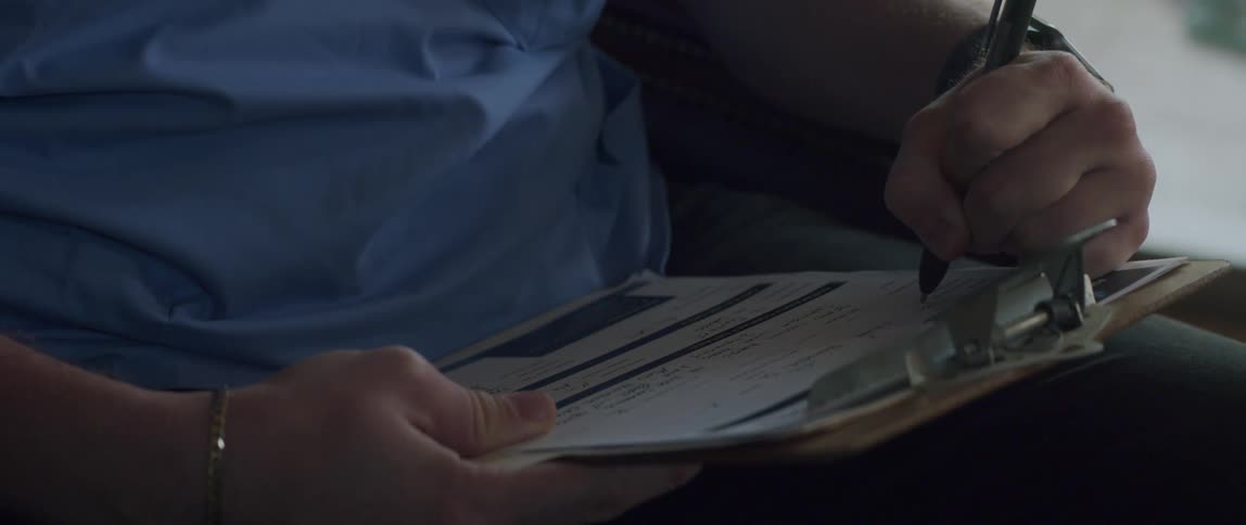 Male doctor sits and fills out form on clipboard