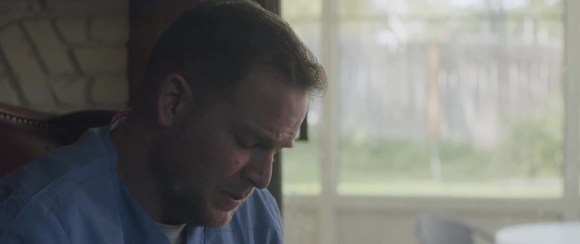 A man is looking ahead intently as he nods his head and then begins to speak