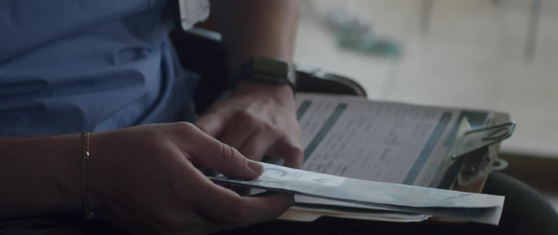 A healthcare worker puts a pamphlet under papers on a clipboard