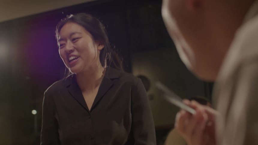 A waitress attends a table and laughs while a man is eating