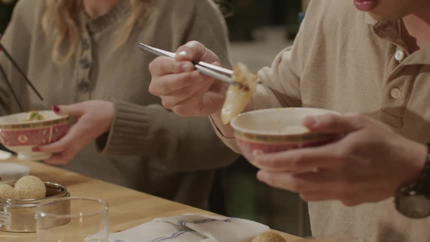 A young couple eating with chopsticks at an asian restaurant