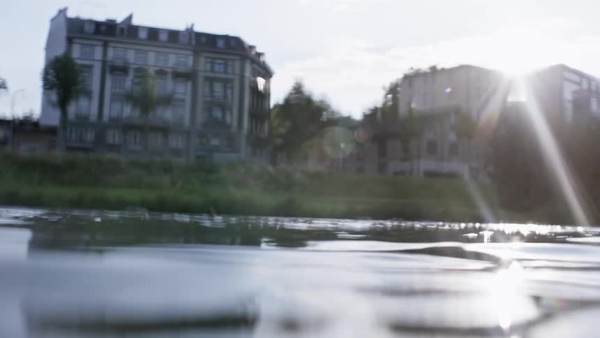 View from inside a crystal clear lake with solar reflection next to a city