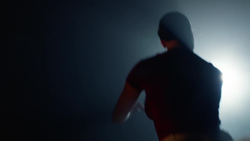 Back view of a ballerina in a dark environment with a light on her dancing