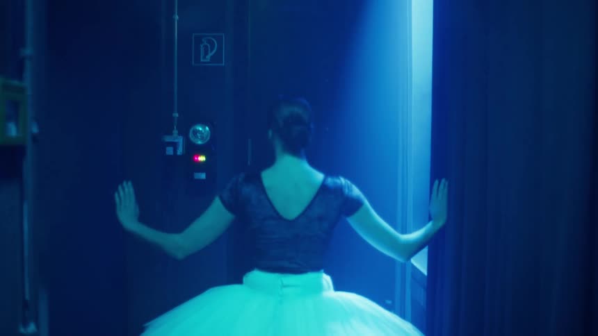 A ballet dancer is dancing behind the curtain