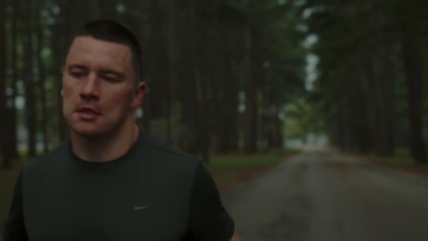 Young man running on a road in the middle of a forest during the day