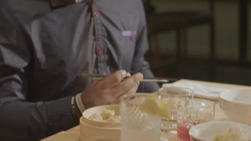 Couple sitting at a restaurant table with chopsticks eating asian cuisine
