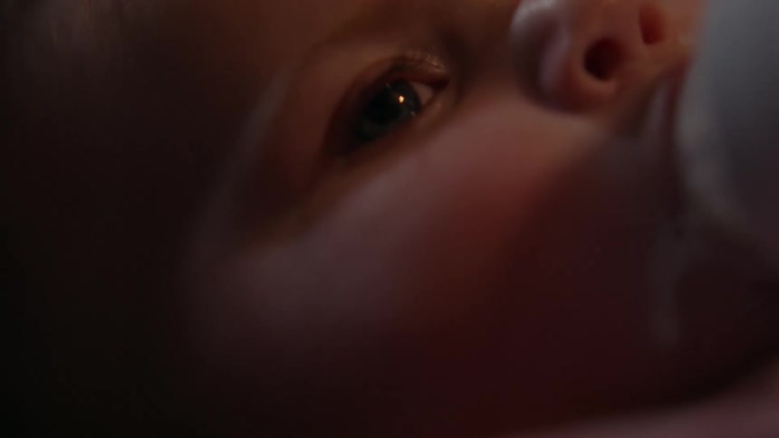 A baby lying down breastfeeding with a bottle