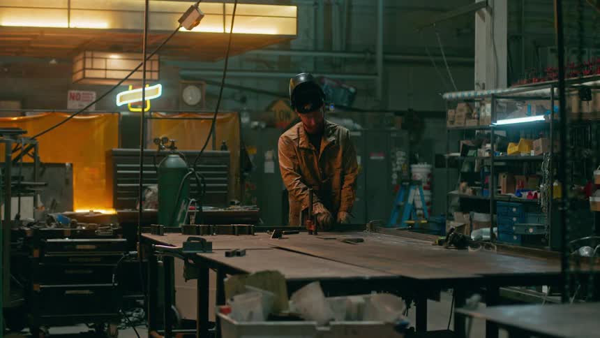 A worker clamps and welds an object