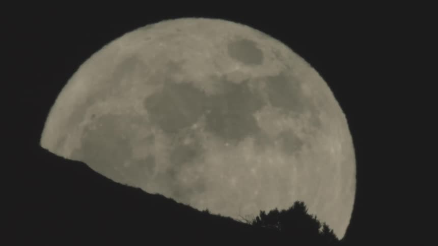 Giant full moon rising over the mountainside