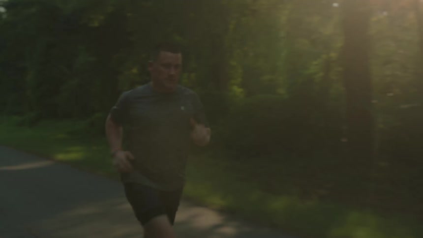 A man running on a road through a forest