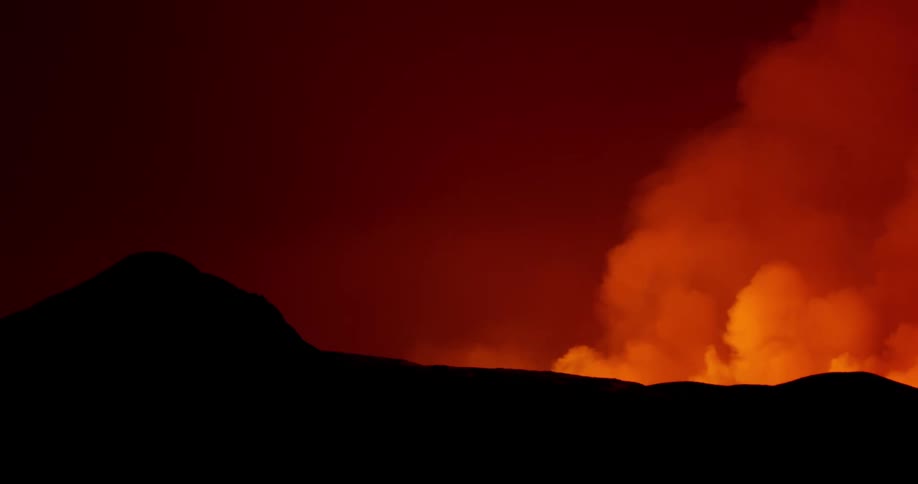 Disaster of a natural fire at night with strong smoke rising amid the silhouette of mountains
