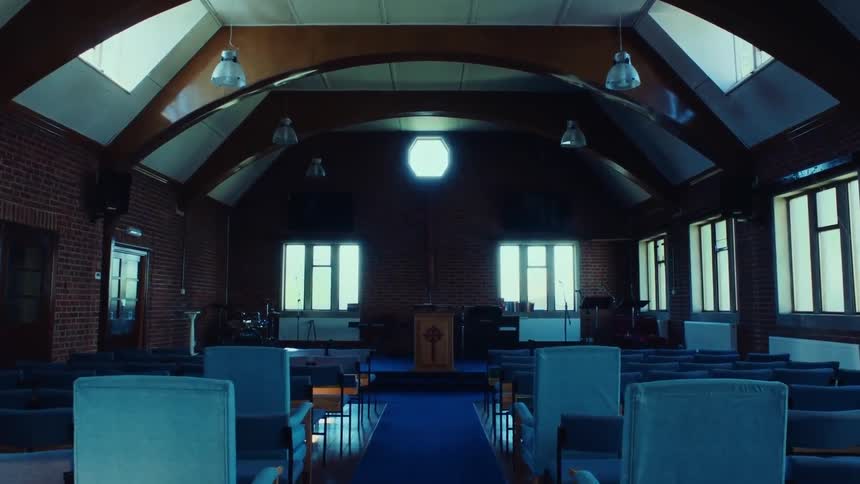 Interior of a church with armchairs and chairs and an altar with a pulpit and musical instruments