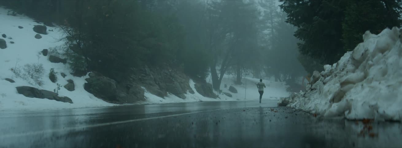 A man runs down a wet road