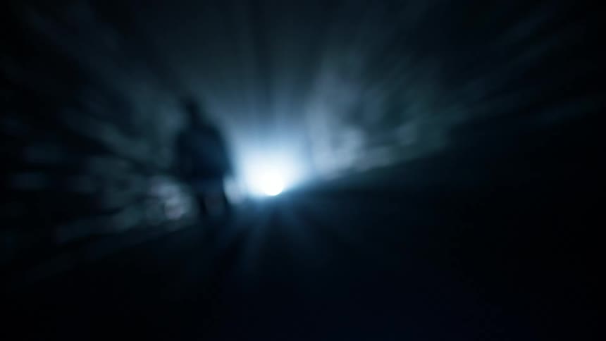 Silhouette of a person walking in a hallway with abstract dark lighting