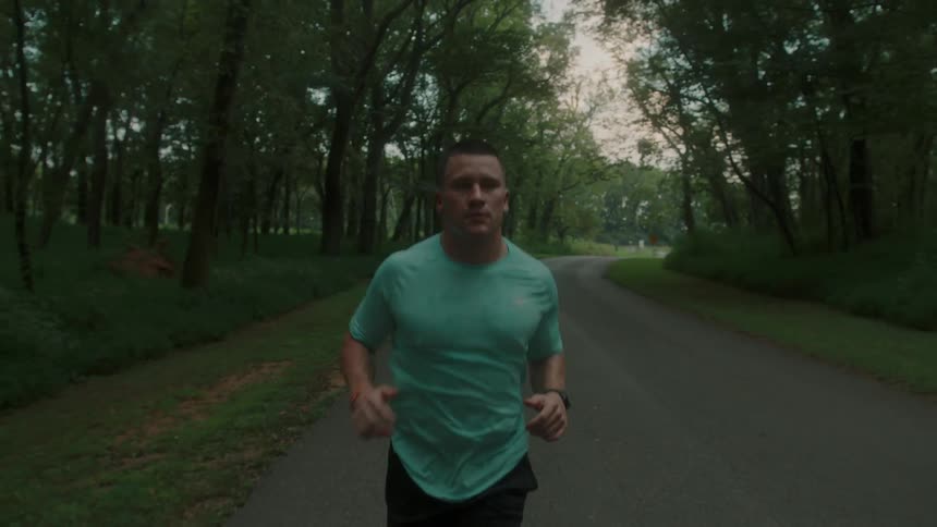 Determined man running on a street surrounded by trees