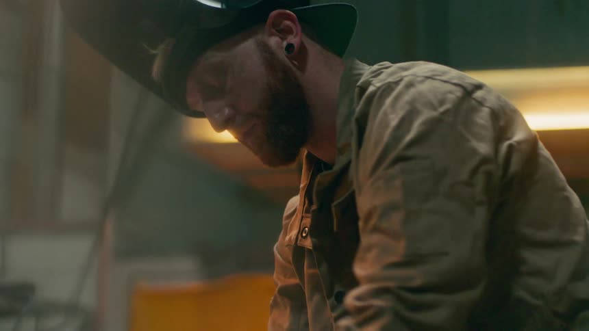Concentrated man with his protective helmet open inside a factory