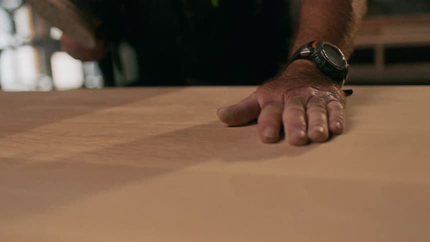 A mans hand passing on a wooden slab
