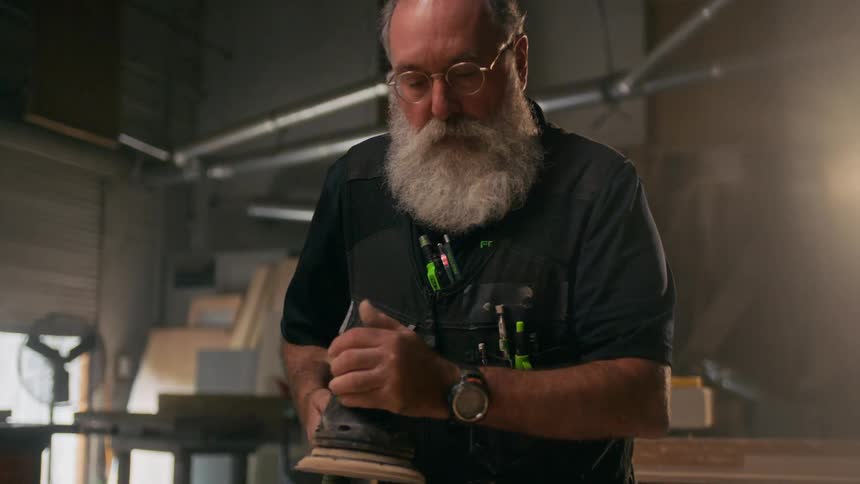 Carpenter man using a machine on a wooden sheet
