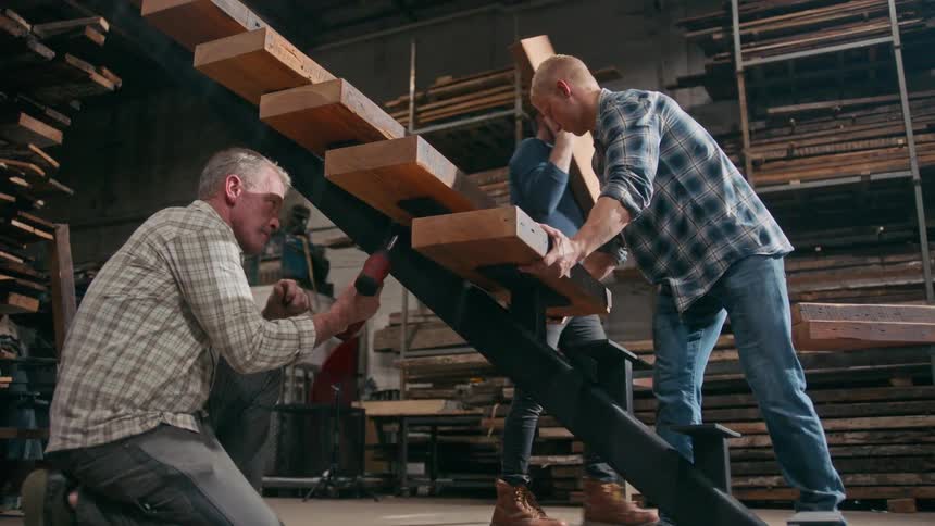Two men are building a staircase with lumber