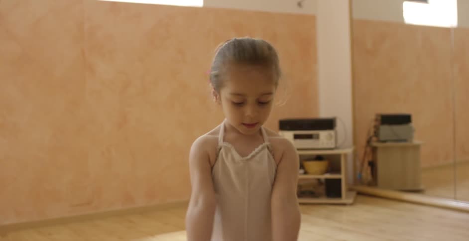 A little girl dressed in a tutu dancing with a teddy bear