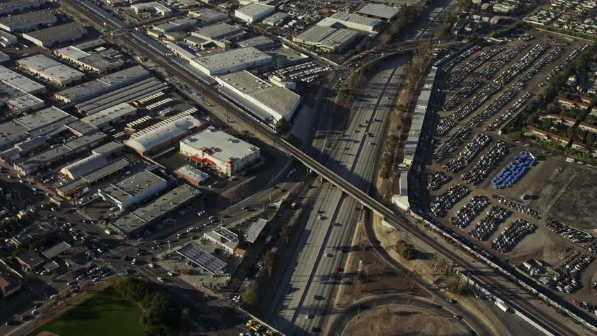 Aerial panorama of a highway through urban cities and factories during the day