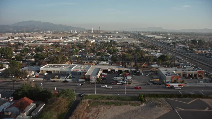 Flying over an airport runway on the edge of an urban city on a blue sky day with few clouds