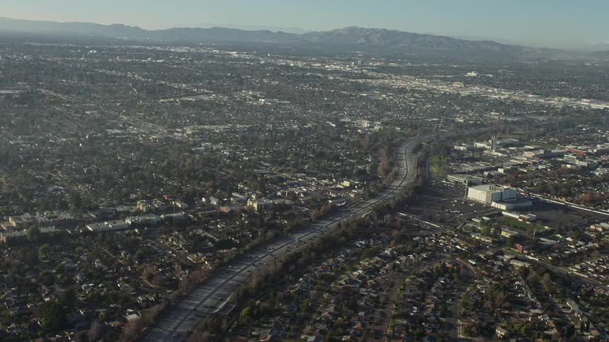 Cars travel the highway between a business district and neighborhoods