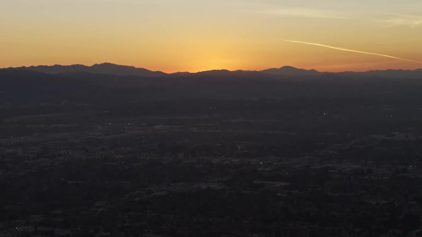 A golden sunset over the mountains next to a small city