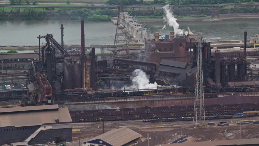 Aerial panorama of a factory with smoke stacks on the edge of a canal in a river dam