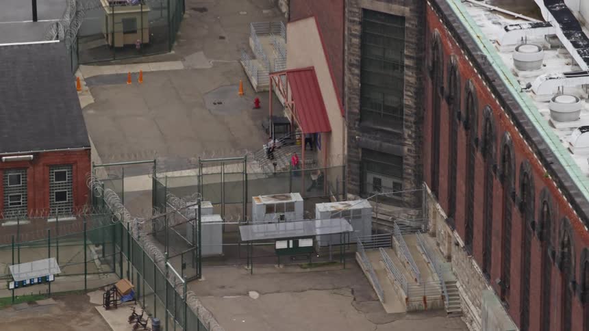 A pair of people exit one of several buildings surrounded by fences