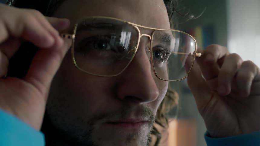 A man adjusts his glasses