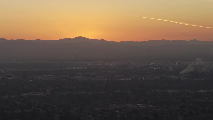Sunset over a city with mountains in the background