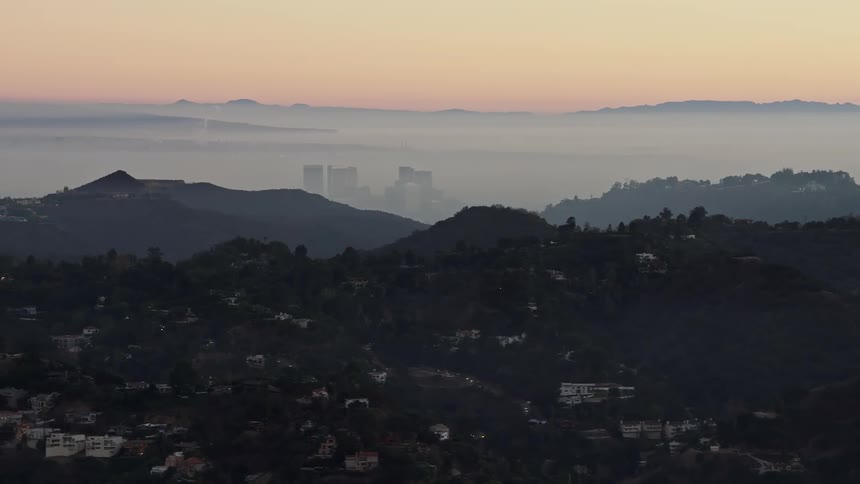 Aerial panorama of a residential city built amidst hills and mountains on a morning with a red sky