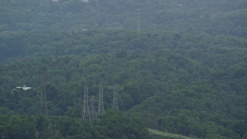 Aerial panorama amidst hills and forests with a flame of fire spewing from a chimney